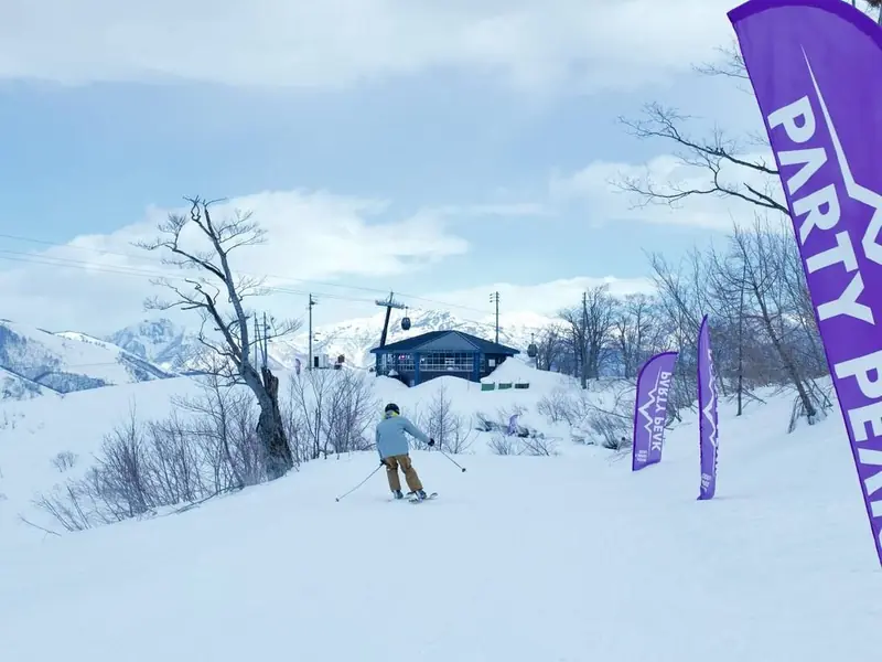 A rider skiing down toward the venue past the Party Peak flags