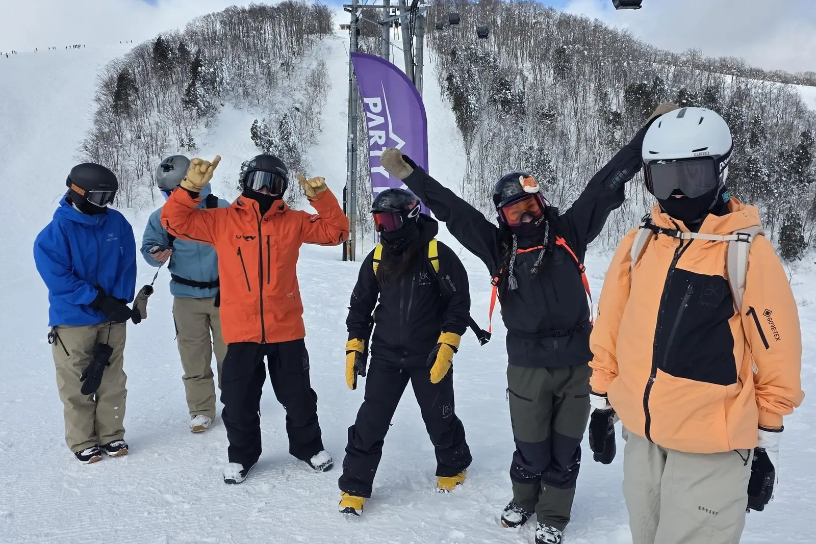 The crew lined up on the piste beside the Party Peak flag