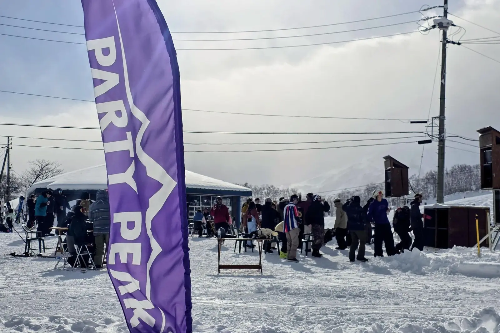 The Party Peak flag flying beside the marquee with the crowd out on the snow