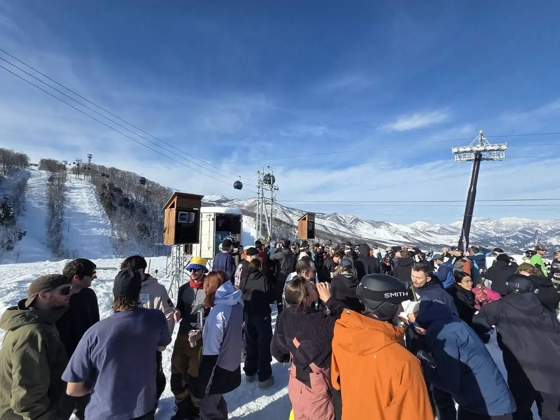 A packed crowd at the booth with the mountain range behind