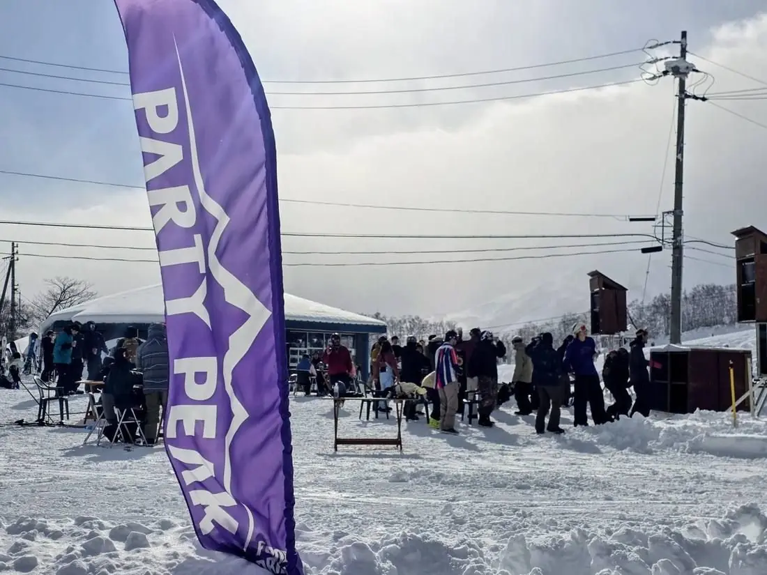 The Party Peak feather flag flying beside the marquee with the crowd behind